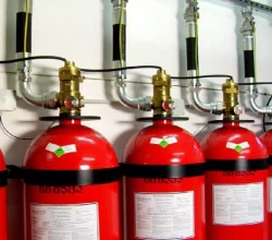 batterie de bouteilles d’extinction automatique à gaz raccordées par flexibles dans un local technique
